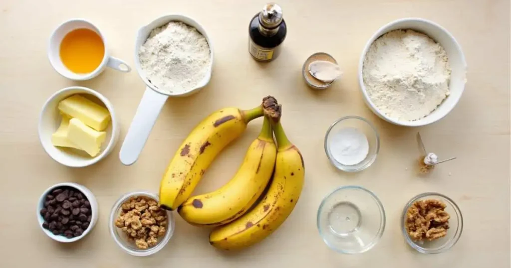 Flat lay of ingredients for a Two Banana Bread Recipe, including ripe bananas, flour, sugar, egg, butter, baking soda, vanilla extract, and optional add-ins like chocolate chips and walnuts.
